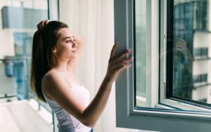 Double glazing vs home insulation series featured image - young lady opens a double glazed window to consider her options