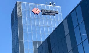 Modern glass office building with reflective façade, featuring the CHN Energy logo and Chinese characters at the top against a clear blue sky.