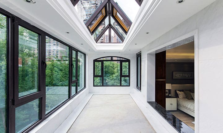 Interior view of a bright modern room illuminated by a roof lantern constructed with LandVac vacuum glazing, alongside black-framed windows.